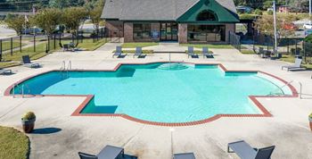 a swimming pool with chairs and a building in the background